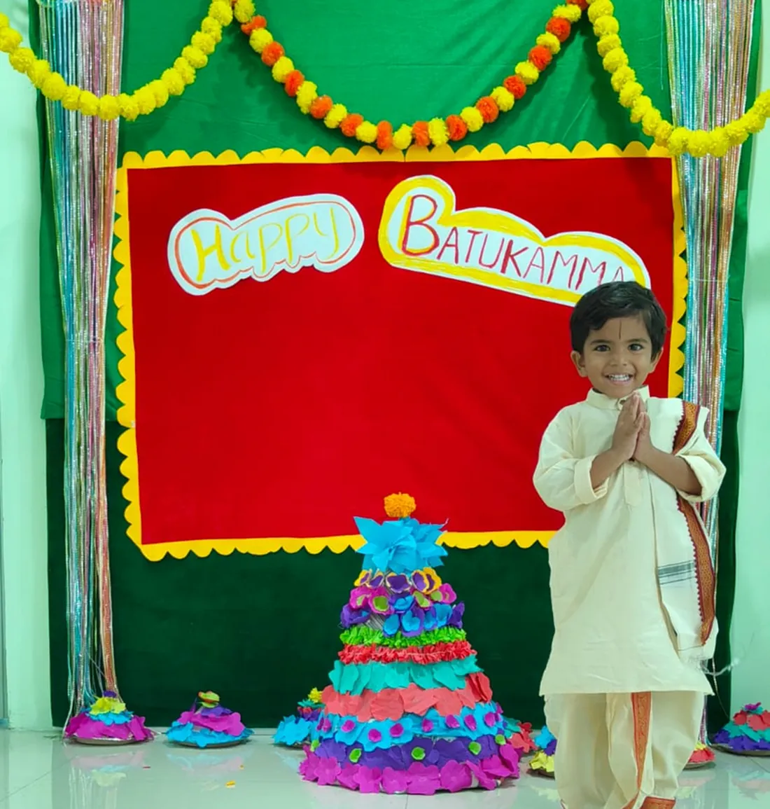 A child in front of a colourful Bathukamma display