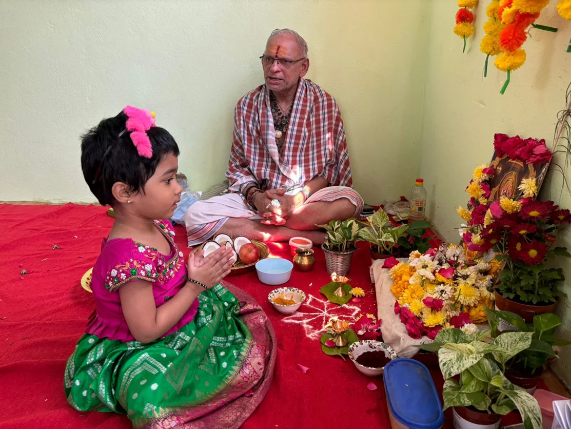 A child performing a puja with her grandfather