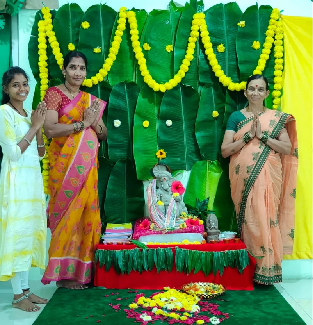 Teachers beside the Vinayaka idol decorated with marigolds